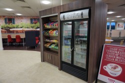 Bespoke retail bay and housing finished in wood effect laminate with LED strip lighting to retail bay