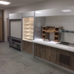 Bespoke soup serving station with corian worktop and woodgrain laminate front panels, bespoke retail bay with slatwall adjustable shelving and LED strip lighting to sides with gloss white laminate fascia panels