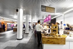 Bespoke servery counters with Corian worktops, gloss laminate front panels, walnut capping corner sections, white emulsion painted walls and columns with feature lighting and stone effect vinyl flooring