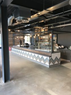 Servery counter with feature tiling band, powder coated steel frame above, polished concrete floor