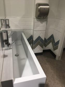 Toilets with feature wall tiling and bespoke staron sink