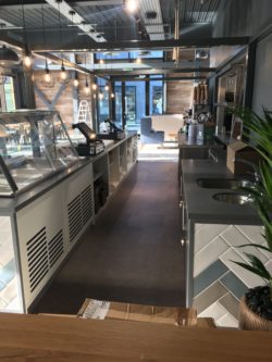 Servery counter with feature tiling band, powder coated steel frame above, safety flooring behind counter