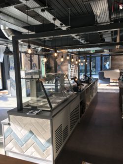 Servery counter with feature tiling band, powder coated steel frame above, safety vinyl flooring behind counter