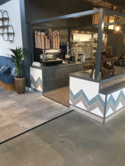 Servery counter with feature tiling band, powder coated steel frame above, polished concrete floor